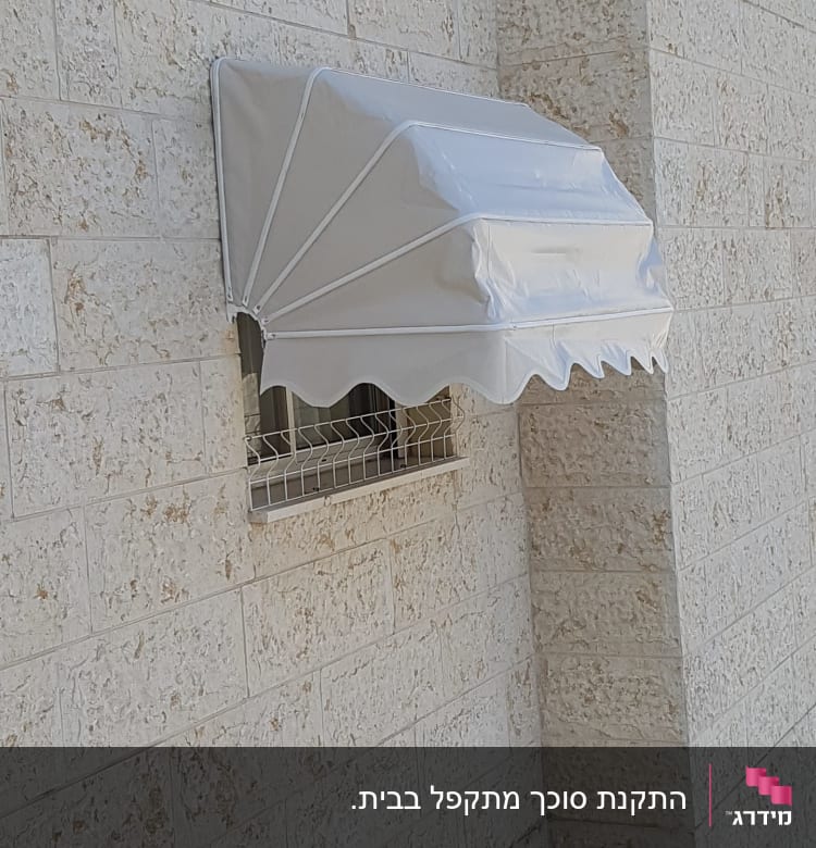 סוכך לבן מעל חלון קיר אבן